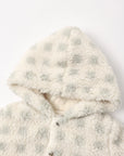 Close-up of a plush sherpa hooded jacket in cream with pale sage green polka dots, featuring a soft lining and snap-button closure.