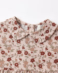 Close-up of a children's dress with a ruffled Peter Pan collar and a dusty floral print on a light beige linen-like fabric, featuring red and brown flowers with green leaves.