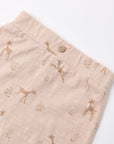 Close-up of a pair of light beige linen shorts with a brown deer and tree print, featuring a single wooden button at the waistband.