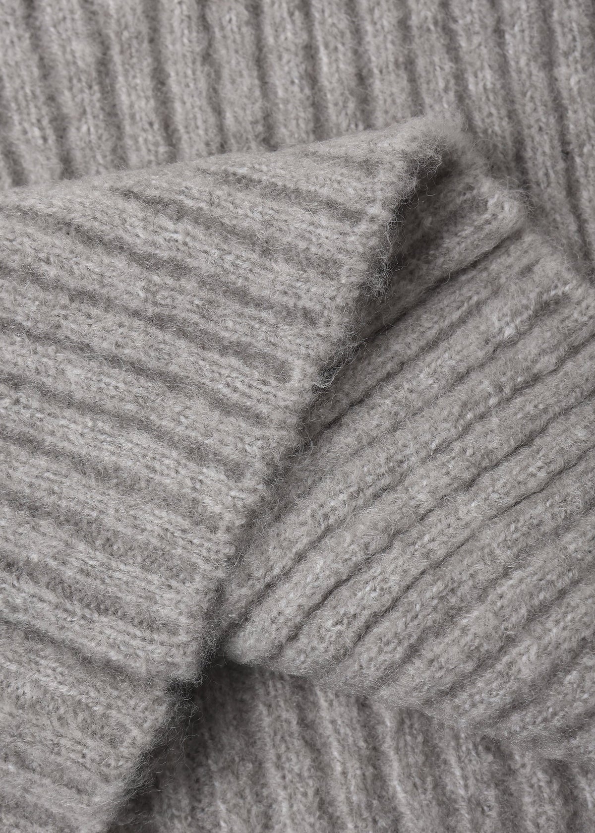 Close-up of a light gray ribbed knit fabric, showing the texture and folds of the material.