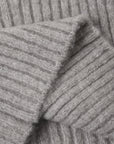 Close-up of a light gray ribbed knit fabric, showing the texture and folds of the material.