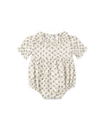 A baby short-sleeve romper in cream with a small dark floral print, featuring a ruffled collar and tie detail, shown flat on a white background.