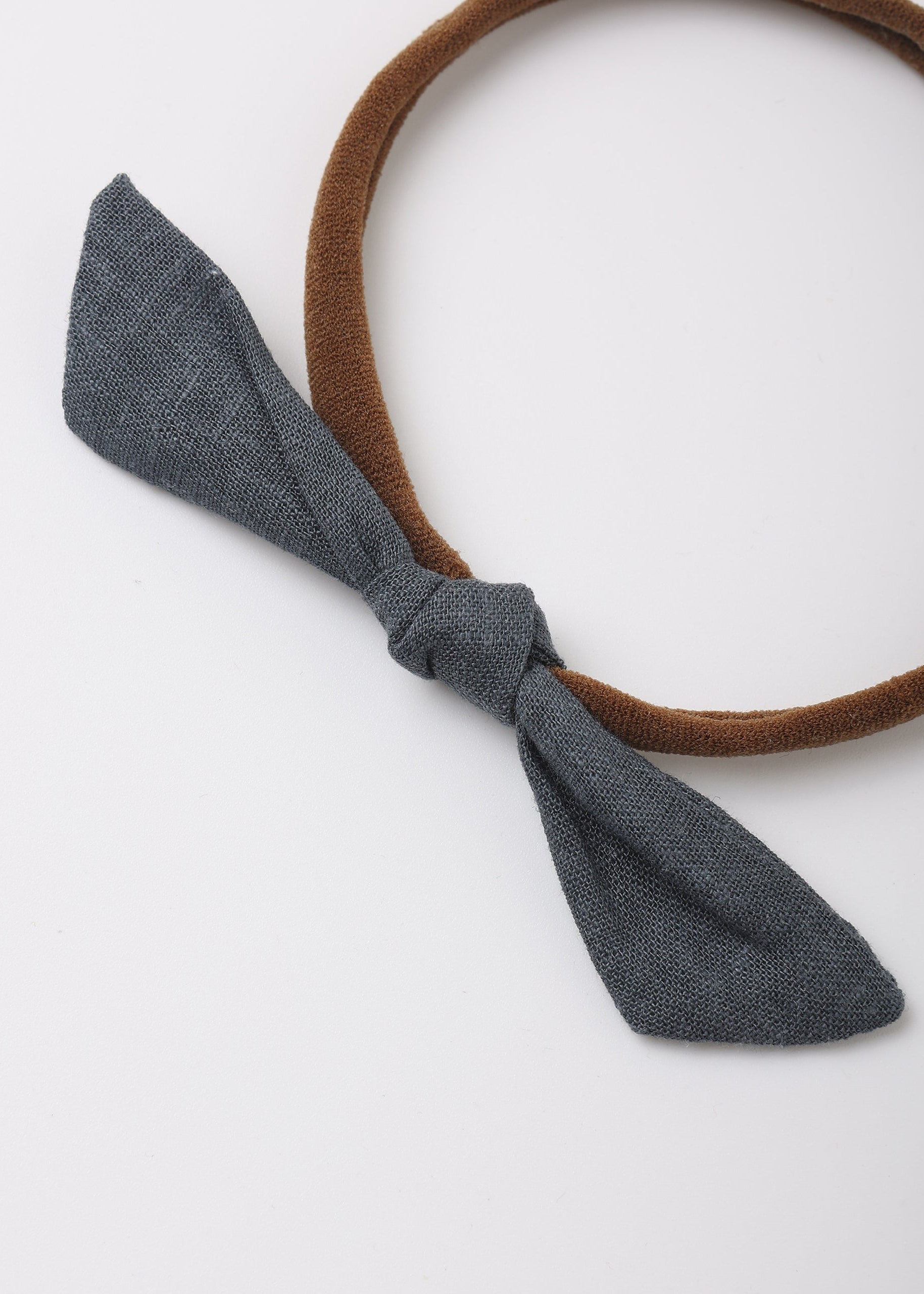 A brown fabric headband with a knotted bow in a textured dark gray fabric, shown on a plain white background.