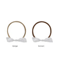 Two white headbands with bows, one beige and one brown, on a white background.