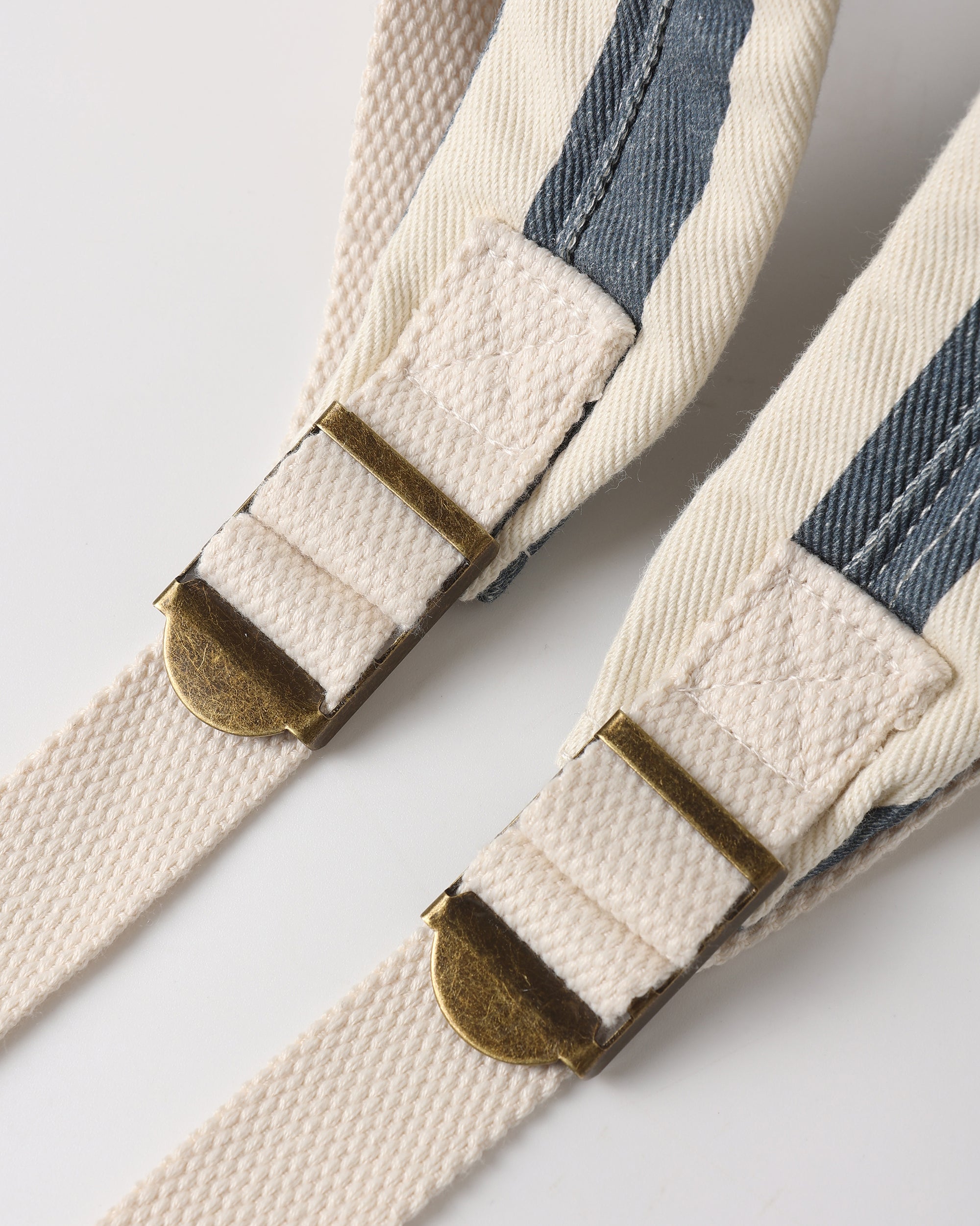 Close-up of a striped belt with brass buckles on a light background