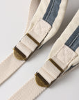 Close-up of a striped belt with brass buckles on a light background