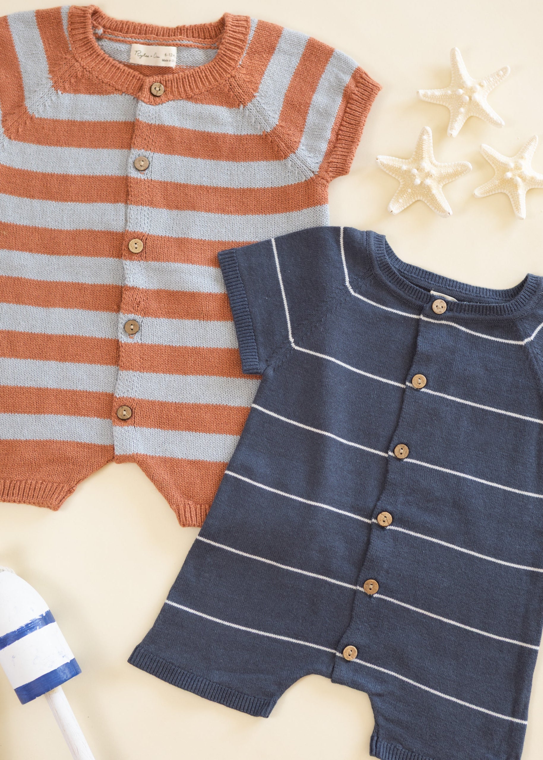 Two striped baby rompers, one orange and gray, the other blue and white, on a light background.