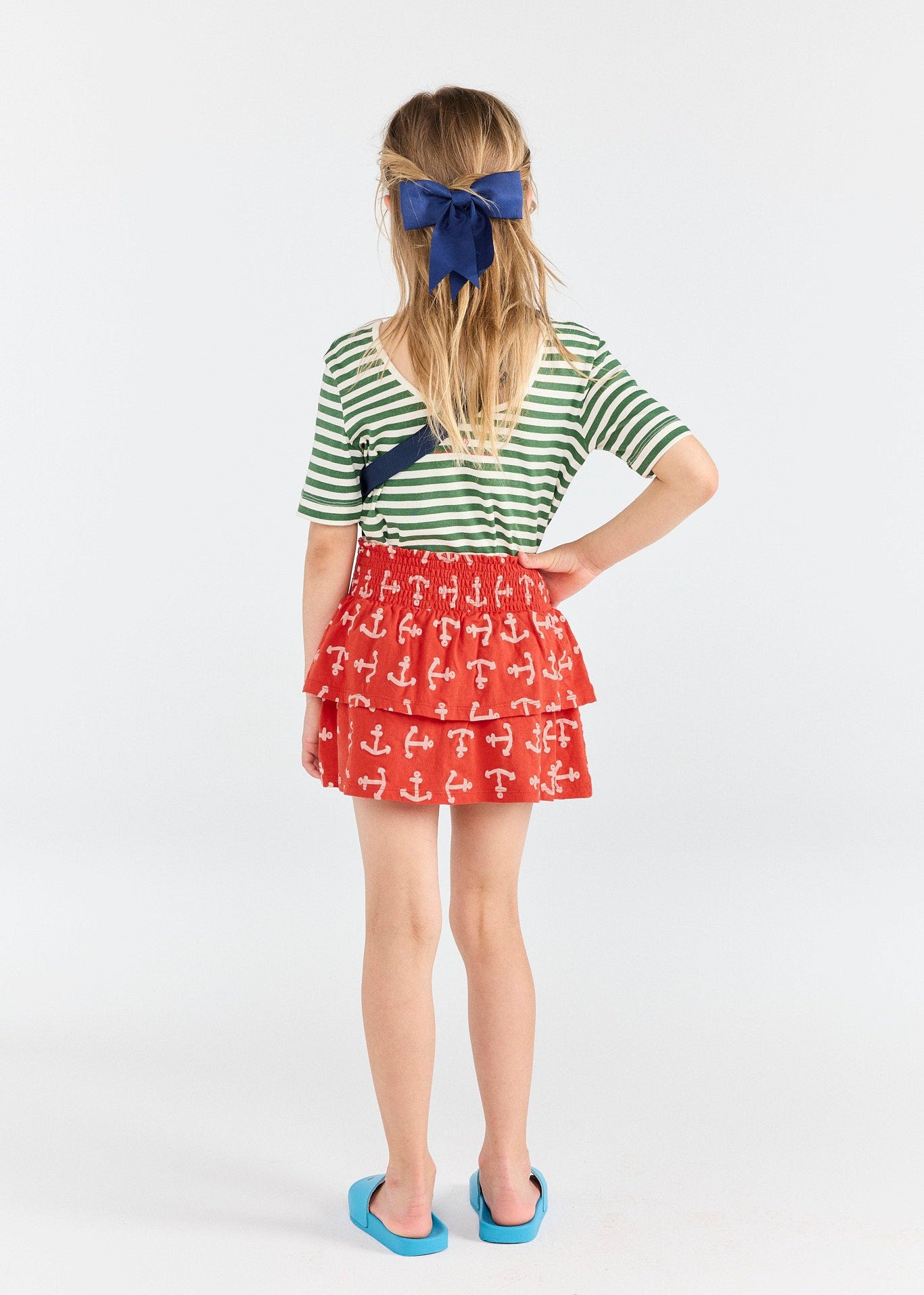 Person wearing a green and white striped shirt with a red skirt featuring anchor patterns on a white background