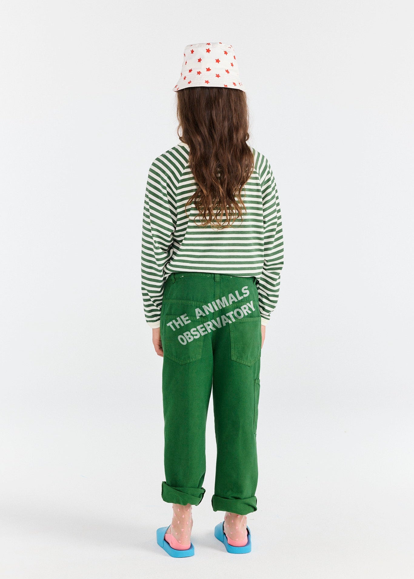 Person wearing a green striped shirt and green pants with 'The Animals Observatory' text, standing on a white background.