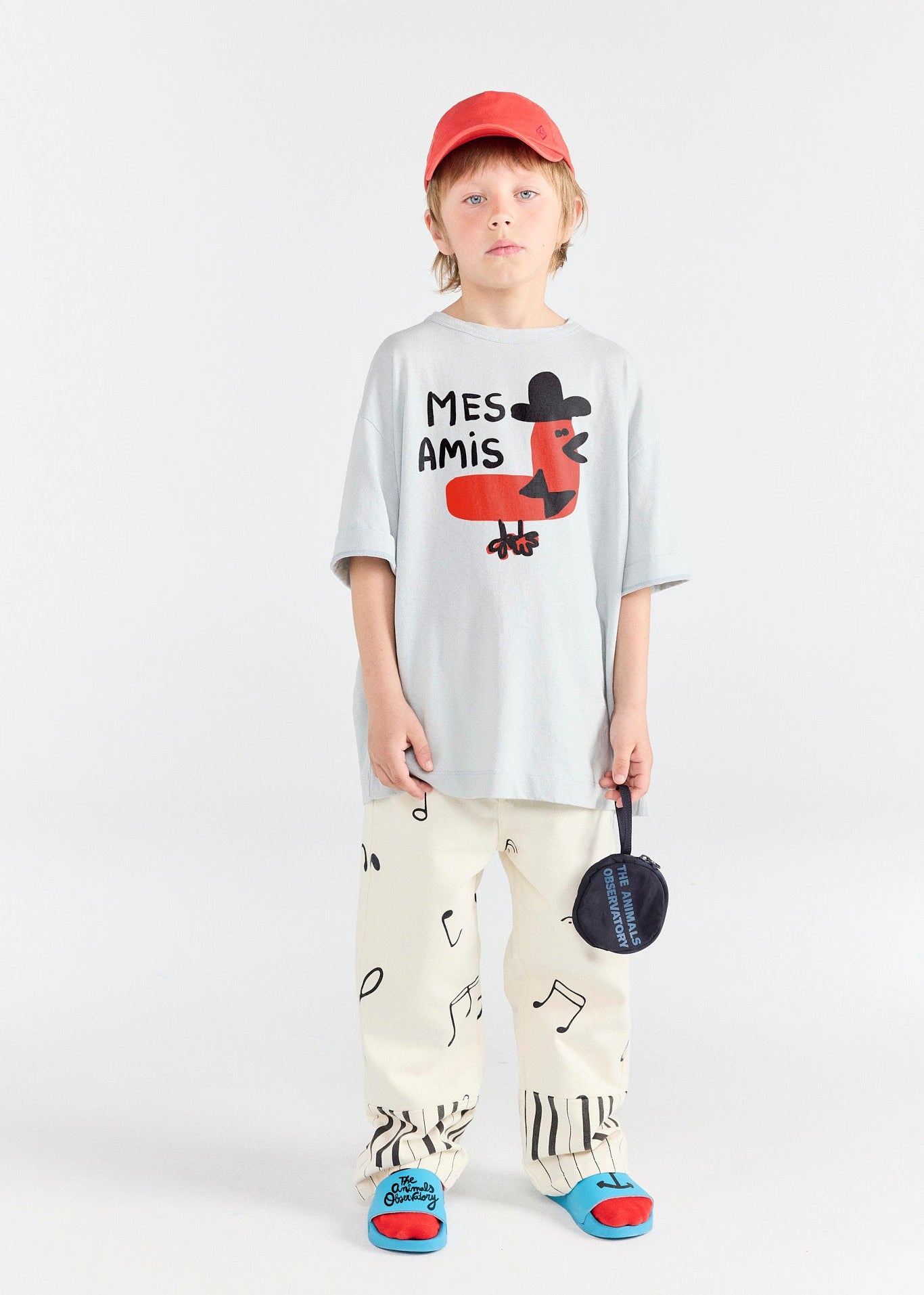 Child wearing a white t-shirt with a graphic design and colorful pants on a white background
