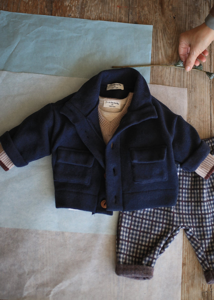 Navy coat and plaid pants on a wooden table