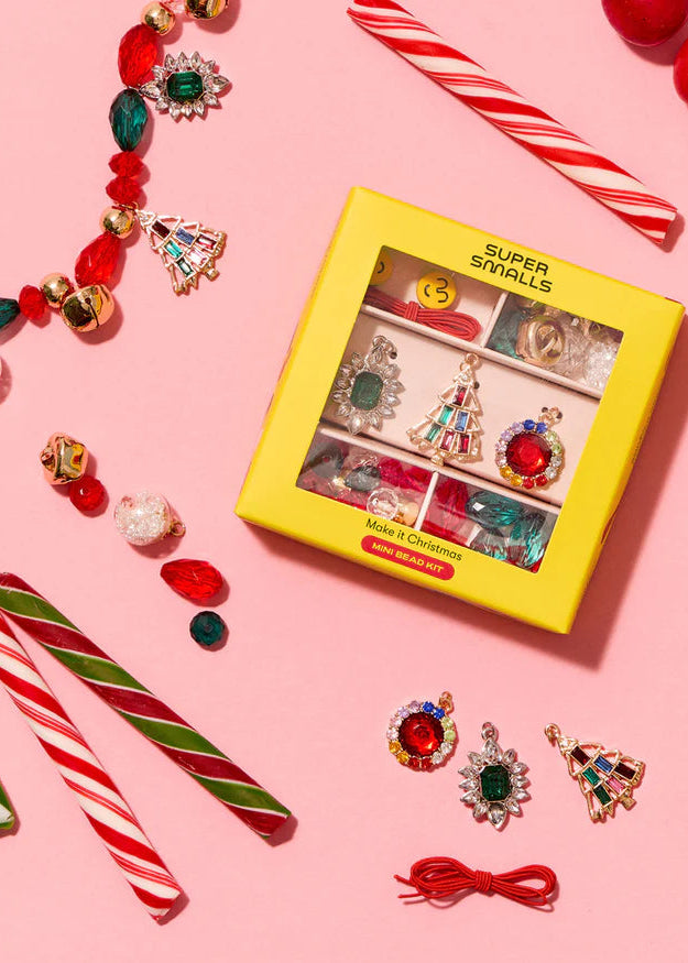 Colorful jewelry set with 'Super Smalls' packaging on a pink background