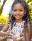 Young girl holding stones outdoors with a blurred background