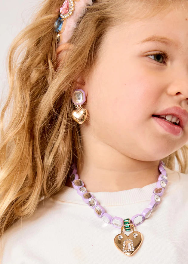 Young girl wearing a colorful necklace and earrings with a white background