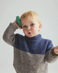 Child wearing a two-tone sweater with a plain background