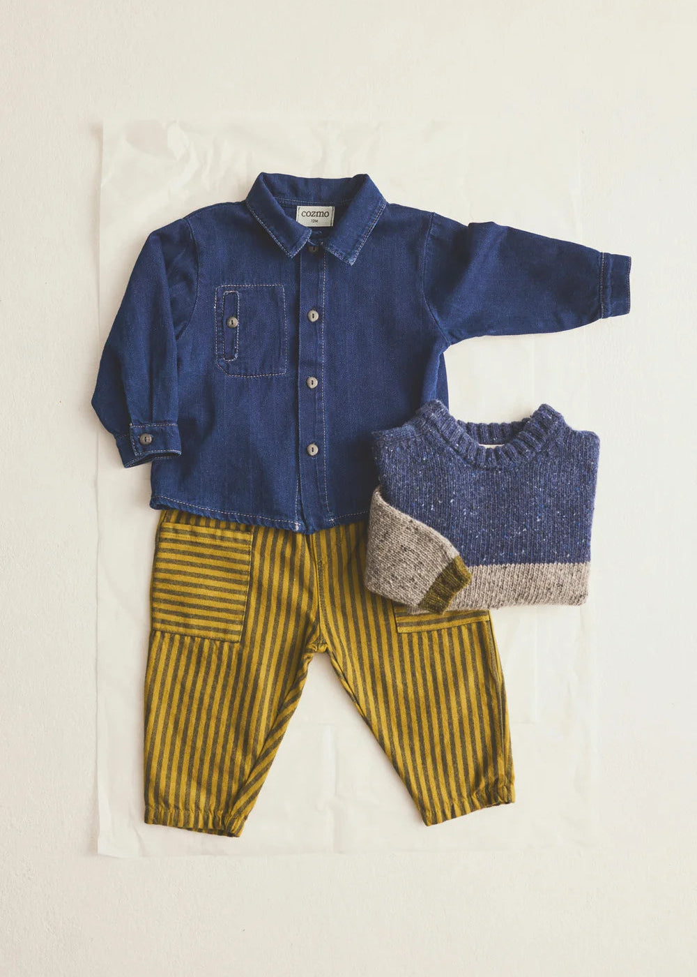 Children's clothing set with blue shirt, yellow striped pants, and gray sweater on a white background