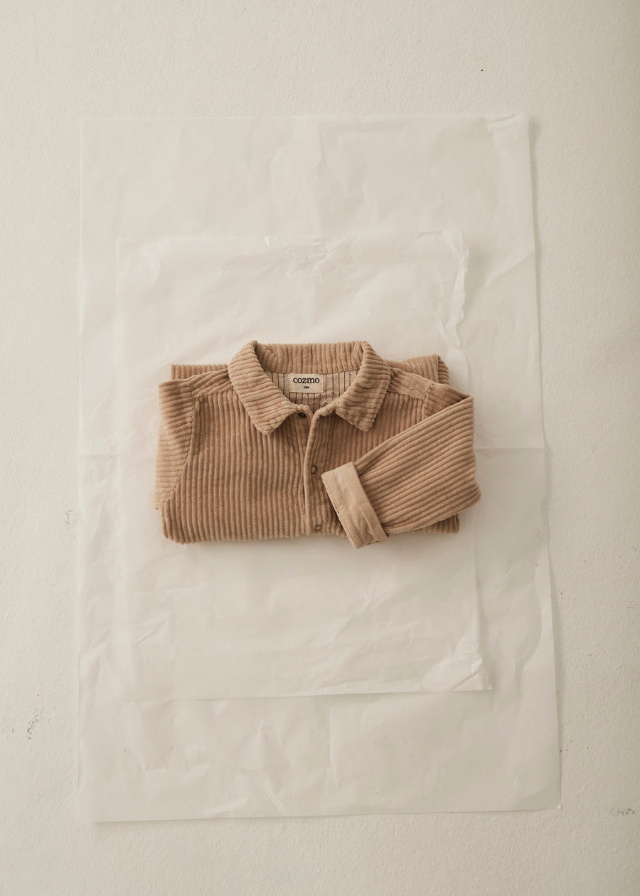 Folded brown sweater on a white fabric background