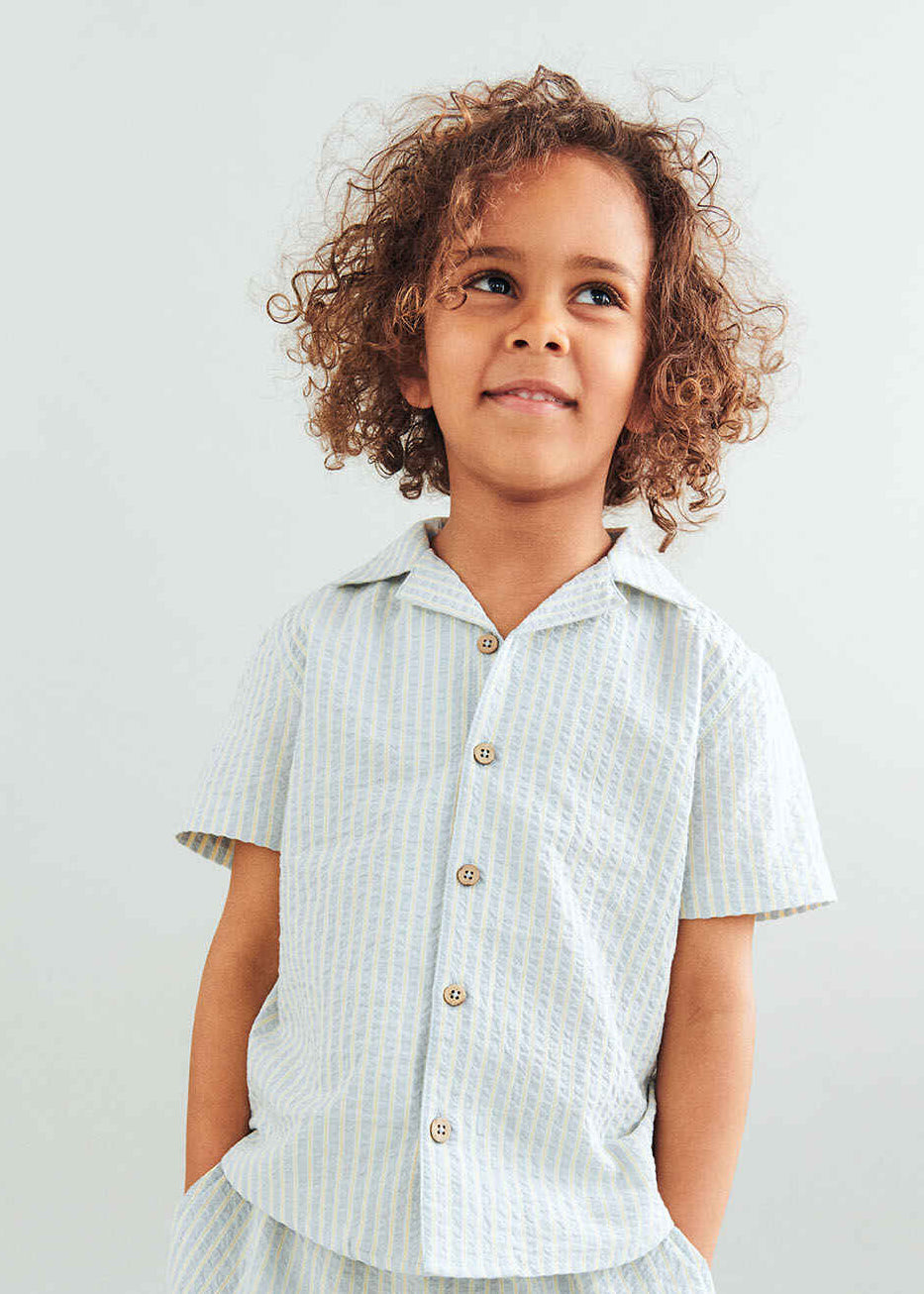 Child wearing a light-colored checkered shirt against a plain background