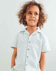 Child wearing a light-colored checkered shirt against a plain background