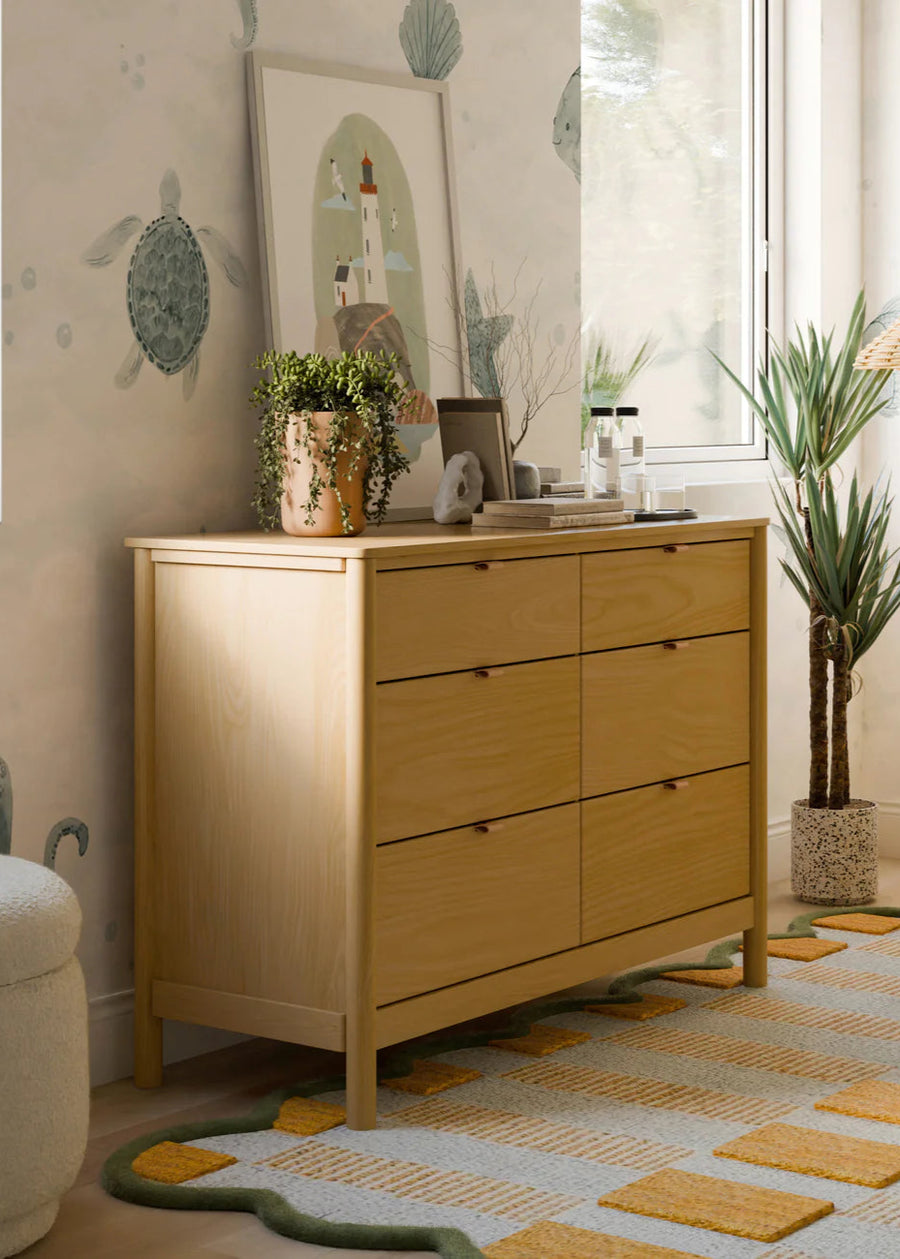 Wooden dresser in a room with turtle-themed wallpaper, rug, and decor items.
