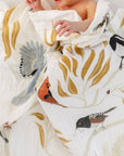 Baby wrapped in a blanket with bird patterns on a white background