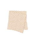 A folded light pink fabric item, likely a blanket or quilt, featuring a dense all-over floral print in soft green, yellow, and pink, set against a plain light gray background.