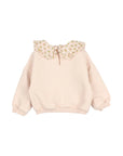 A light pink long-sleeve sweatshirt for a toddler girl, featuring a large ruffled Peter Pan collar decorated with a small yellow and green floral pattern.