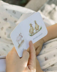 Hand holding a card with illustrations of ducklings against a blurred natural background