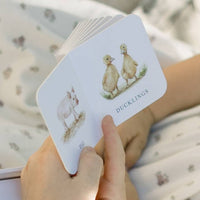 Hand holding a card with illustrations of ducklings against a blurred natural background