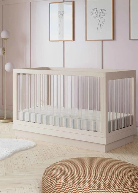 Nursery room with a white crib, light pink walls, and decorative elements.
