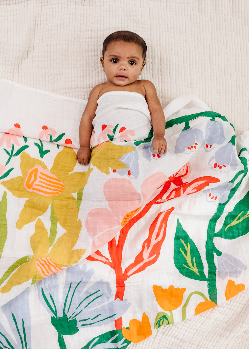 Baby wrapped in a floral blanket on a soft surface