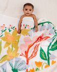 Baby wrapped in a floral blanket on a soft surface