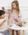 Two children playing with a toy barber set on a white table.