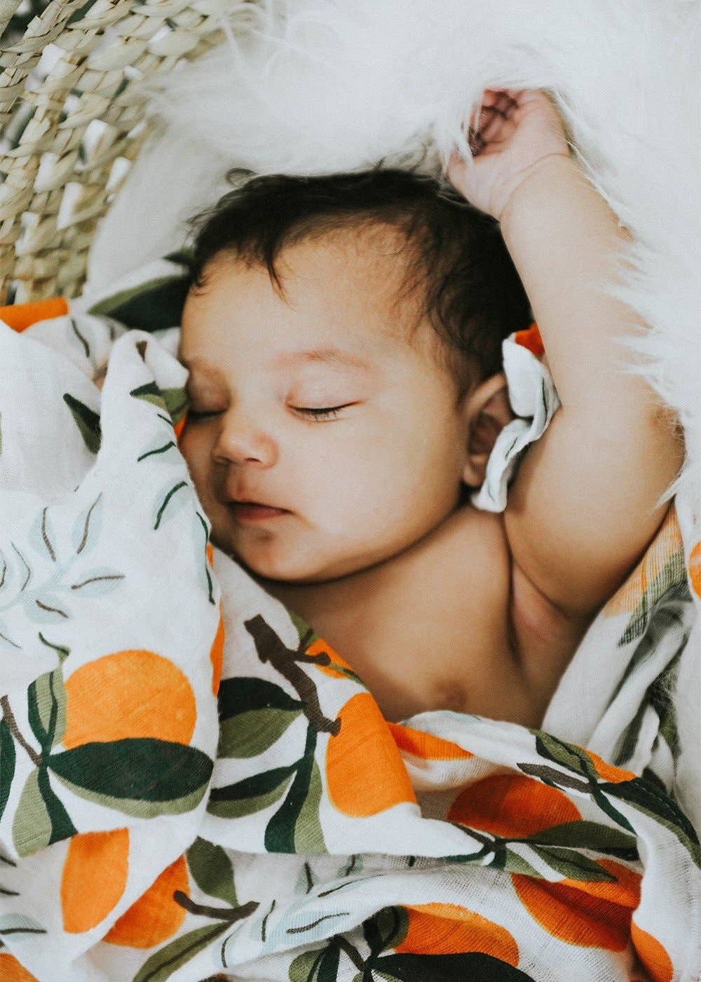 Newborn baby wrapped in a blanket with orange and leaf pattern
