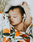 Newborn baby wrapped in a blanket with orange and leaf pattern