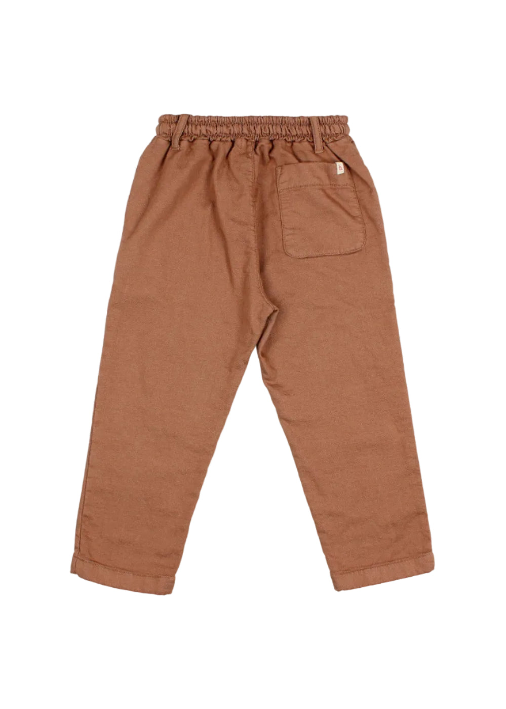 A pair of children's trousers in a warm rust brown color, shown from the back. The pants feature an elastic waistband, a side pocket, and a back pocket with a small white brand tag.