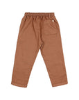 A pair of children's trousers in a warm rust brown color, shown from the back. The pants feature an elastic waistband, a side pocket, and a back pocket with a small white brand tag.