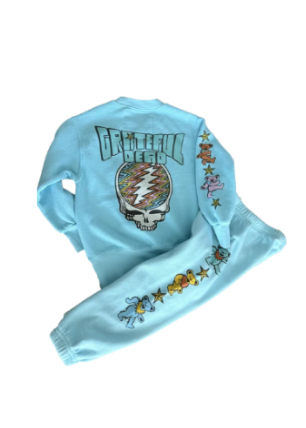 A light blue Grateful Dead sweatshirt and matching sweatpants set. The back of the sweatshirt features a large Grateful Dead skull graphic with a multicolor lightning bolt and the words 'GRATEFUL DEAD'.