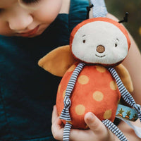 Child holding a plush toy with a blurred natural background