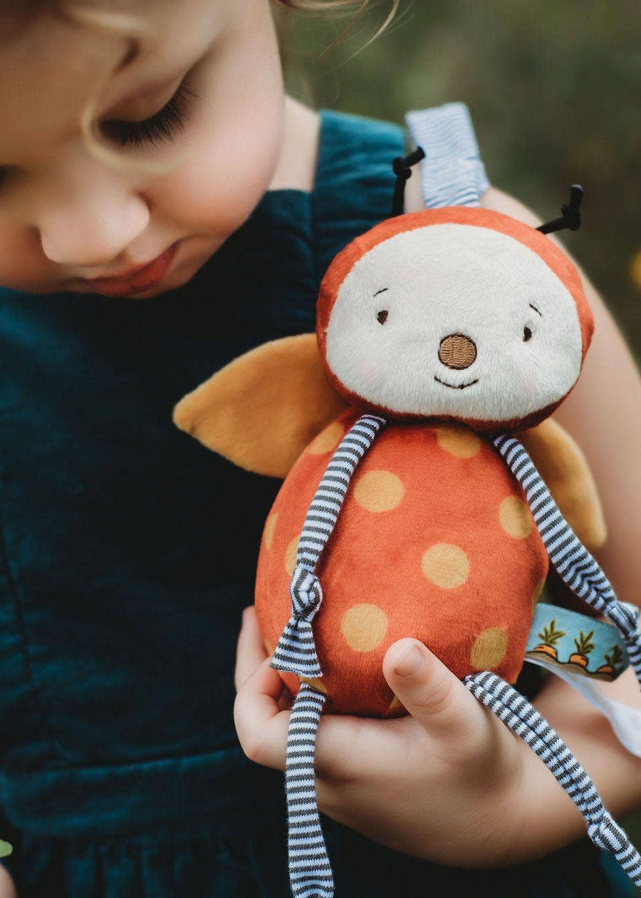 Child holding a plush toy with a blurred natural background