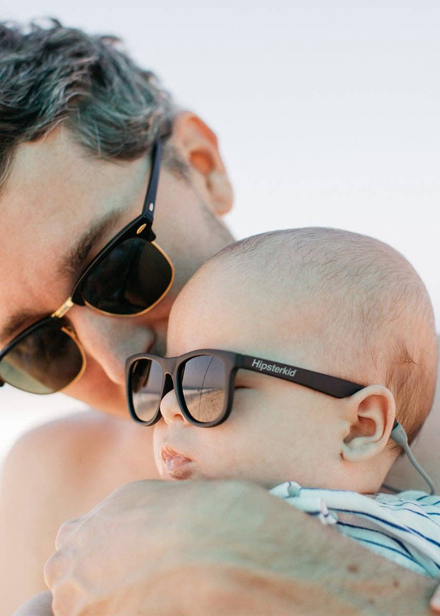 Man and baby wearing sunglasses with a blurred background