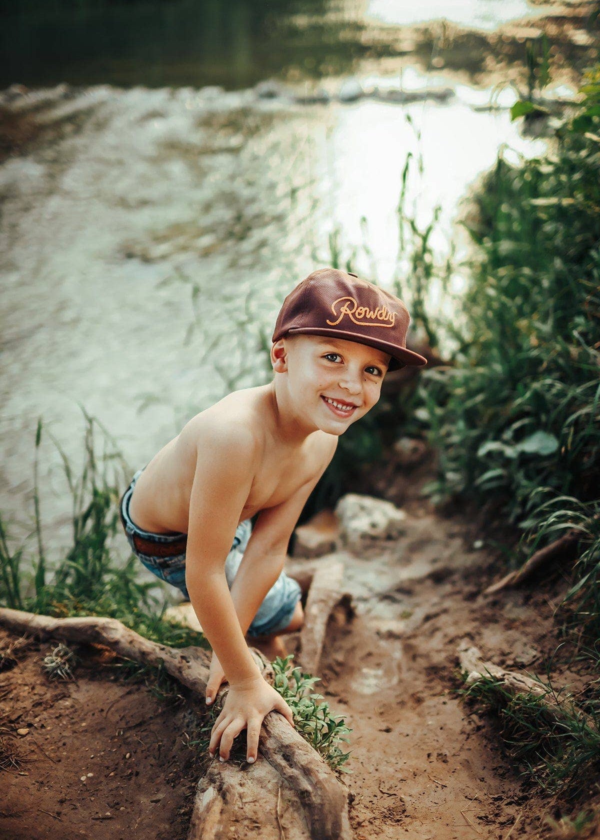 Young boy wearing a cap by a stream
