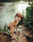 Young boy wearing a cap by a stream