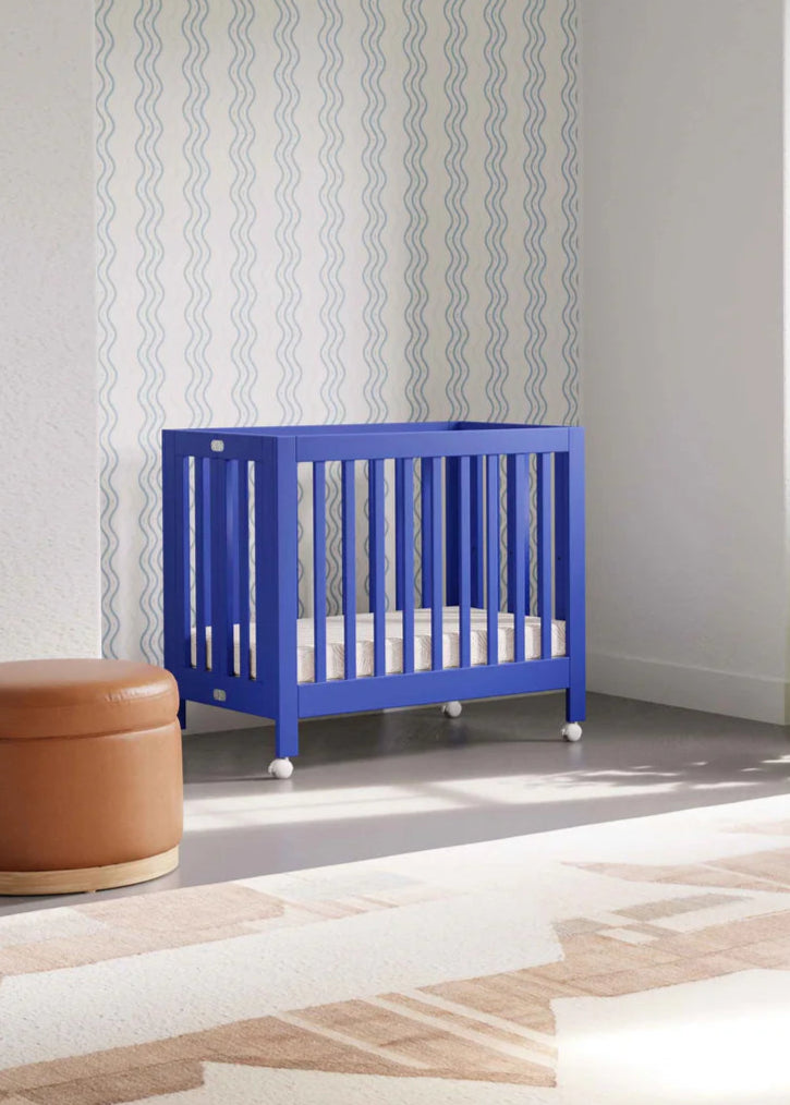 Modern nursery with a blue crib, brown ottoman, and decorative plants.