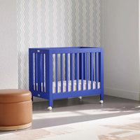 Modern nursery with a blue crib, brown ottoman, and decorative plants.
