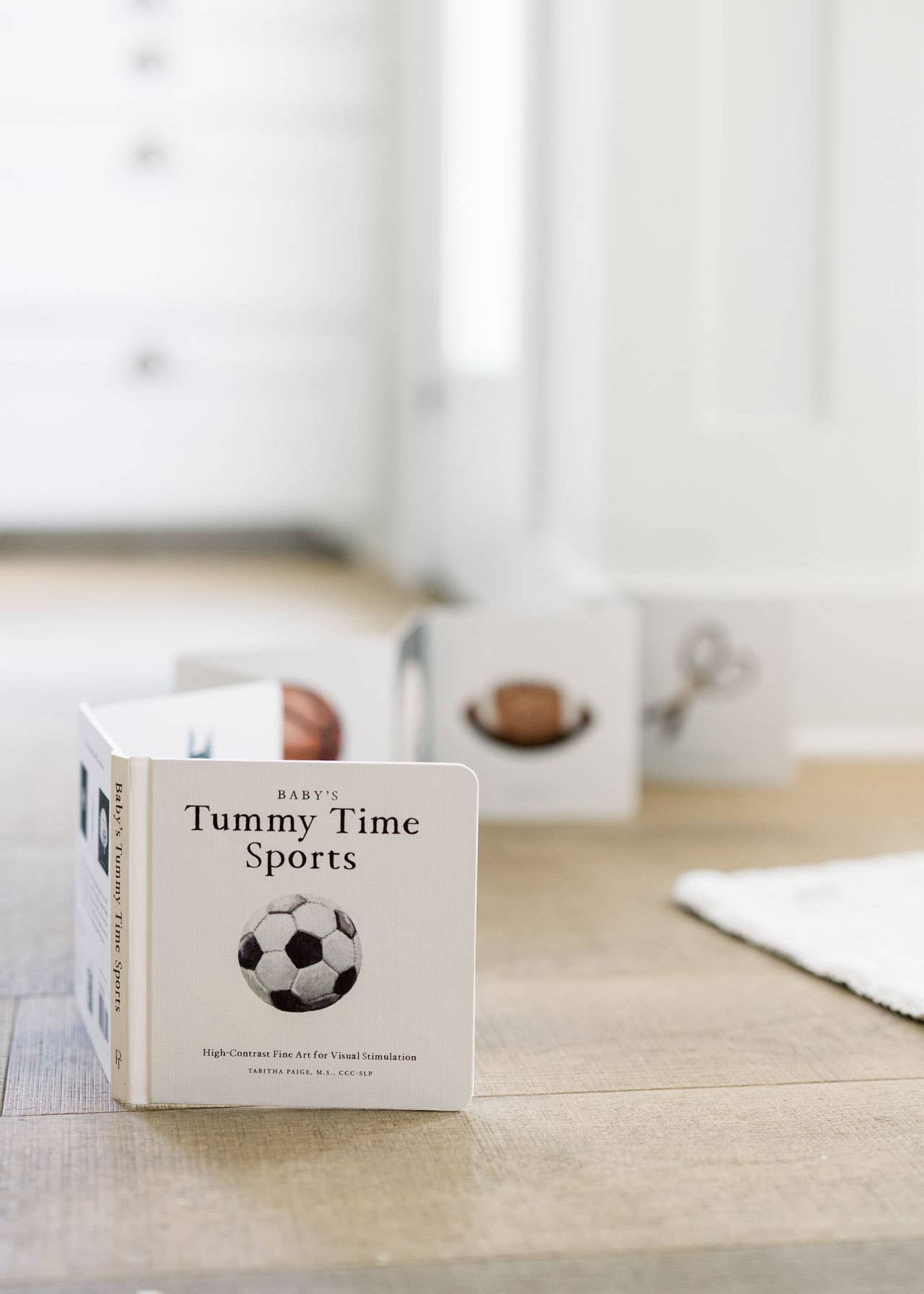 Children's book titled 'Tummy Time Sports' on a wooden surface with a blurred background