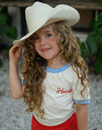 Child wearing a cowboy hat and 'Howdy' shirt outdoors