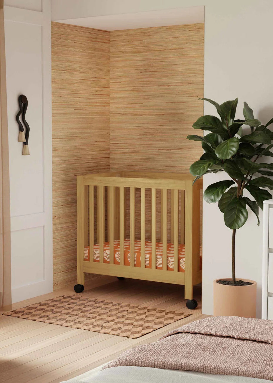 Nursery room with wooden crib, plant, and armchair.