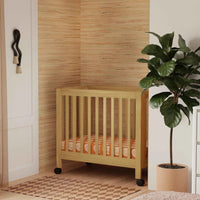 Nursery room with wooden crib, plant, and armchair.
