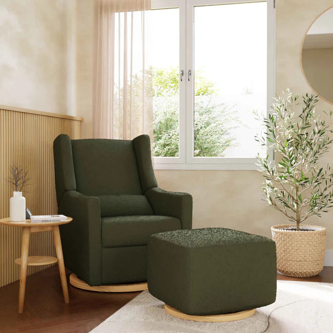 Green armchair and ottoman in a living room with a window and plants.